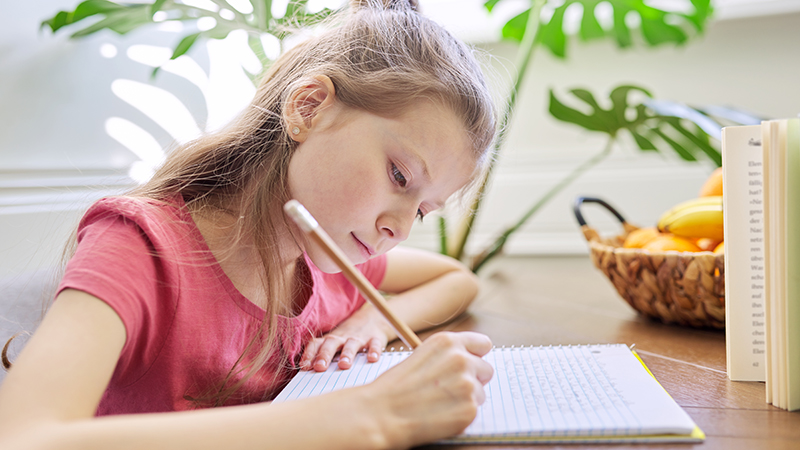 Imagen de una niña en una clase escribiendo
