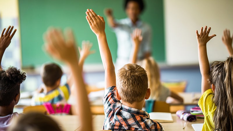 Imagen de niños levantado la mano en una clase